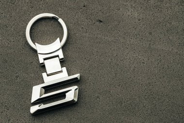 Koyu beton arka planda 5 numaralı metal araba anahtarı