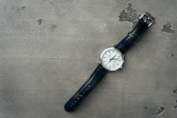 Male mechanical watch on dark concrete surface