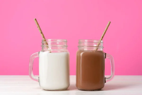 Стеклянные банки со вкусом молочных коктейлей на розовом фоне — стоковое фото
