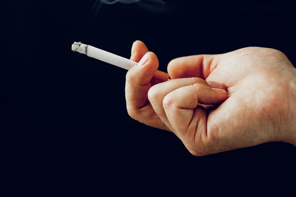 Mužská ruka s hořící cigaretou na černém pozadí — Stock fotografie