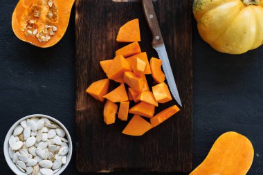 Masadaki tahta tahtada çiğ balkabağı parçaları kes.