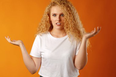 Şaşırmış genç bir kadın bilmediğine dair işaretler yapıyor.