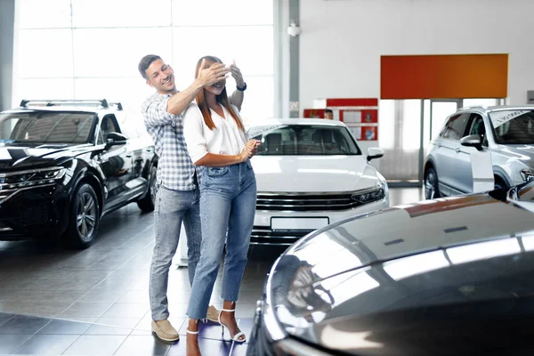Young happy couple just bought a new car in a dealership
