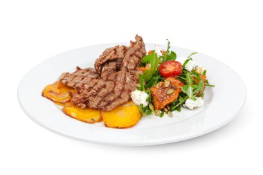 Beyaz arka planda kızarmış patatesli ızgara biftek dilimleri.