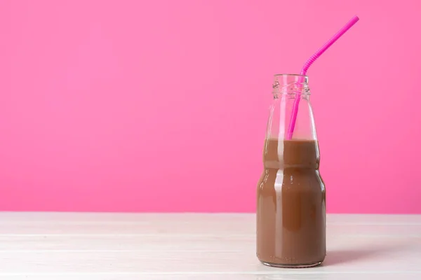 Шоколадное молоко или молочный коктейль в стеклянной бутылке на розовом фоне — стоковое фото