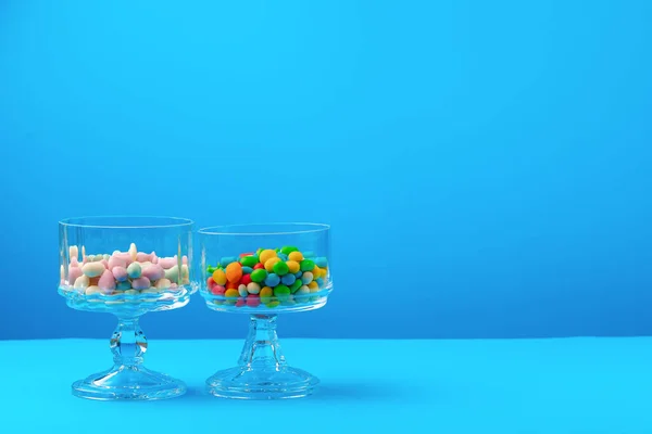 Recipientes de vidro com doces coloridos contra fundo azul — Fotografia de Stock