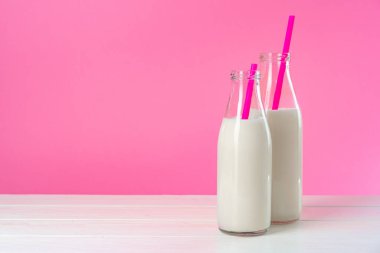 Pembe arka planda iki bardak süt ya da milkshake.