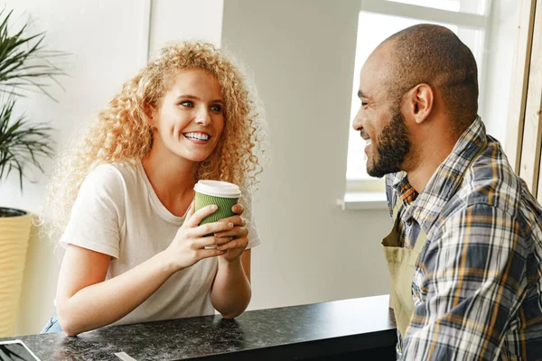 Mulher loira sorridente conversando com um garçom de um café no balcão — Fotografia de Stock