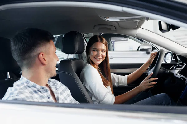 Pareja joven eligiendo su coche nuevo en una tienda de coches — Foto de Stock