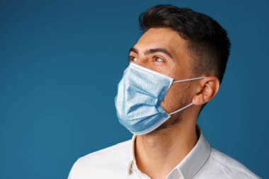 Tıbbi maske takan yakışıklı, melez bir adam.