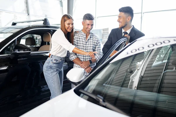 Unga par väljer en bil hos återförsäljaren med manager hjälpa — Stockfoto