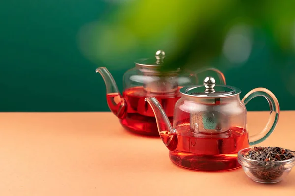 Bule de vidro com chá preto no fundo da folhagem borrada — Fotografia de Stock