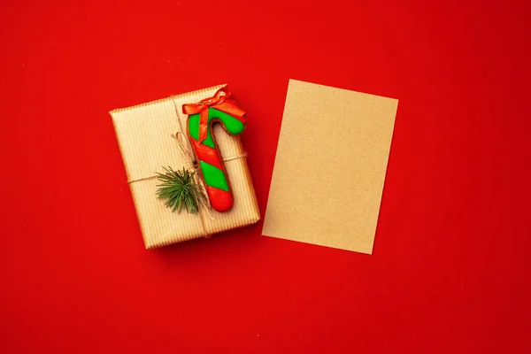 Blank sheet of paper with Christmas gift and gingerbread cookies on red background
