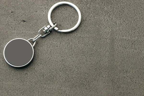 Μενταγιόν μεταλλικό κλειδί σε σκούρο φόντο από τσιμέντο — Φωτογραφία Αρχείου