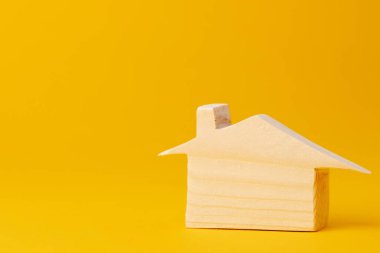 Sarı arka planda ahşap küçük ev modeli