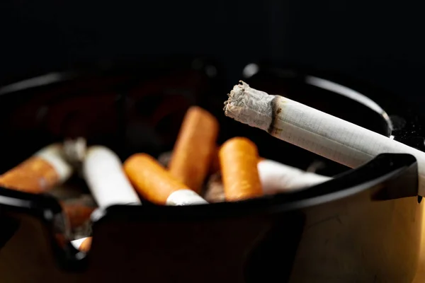Spalování cigaret v černém popelníku — Stock fotografie