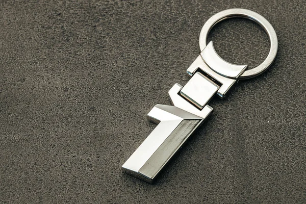 Koyu beton arka planda bir numaralı metal araba anahtarı — Stok fotoğraf