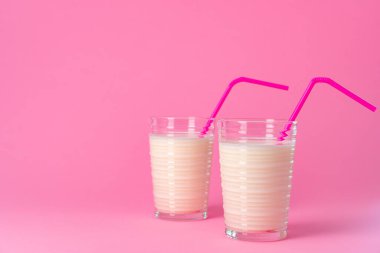 Pembe pastel arka planda taze sütle kaplı cam eşyalar.