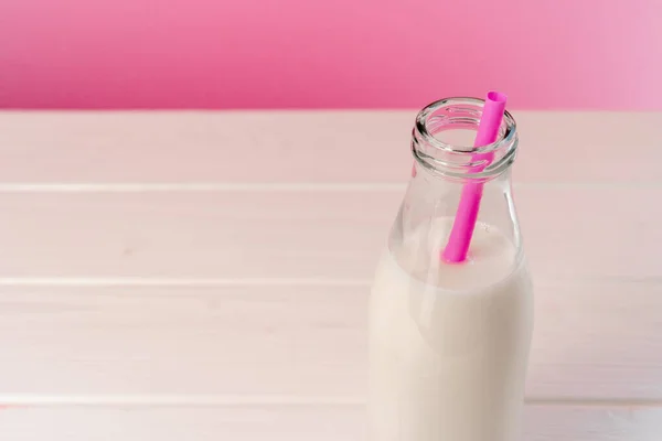 Botella de vidrio de leche sobre fondo rosa — Foto de Stock