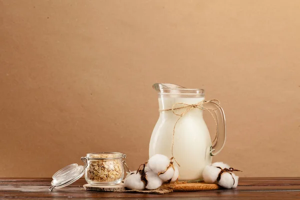 Pitcher of fresh milk on wooden table against beige background