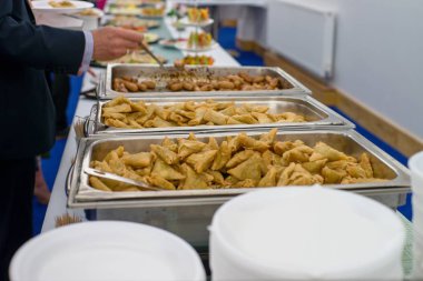 Bayram. Tablo kadar dolu. Kızarmış rulolar, soslu sosisler ve kaplama. Kaşıkla kol.