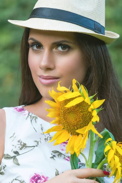 Close-up portrait of brunette woman with sunflower in her hand