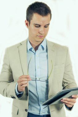 Ciddi genç erkek dijital tablet kullanarak haber veya bilgileri tablet bilgisayarında kontrol ediyor