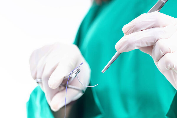 Doctor holding surgical forceps suture needle, suturing material