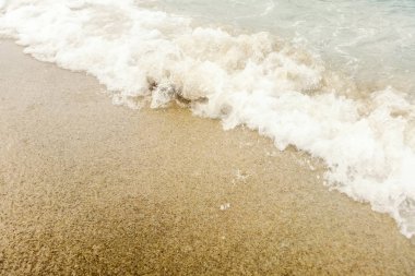 Kumlu sahilde mavi okyanus dalgası Yaz Arkaplanı 'nı kapatır