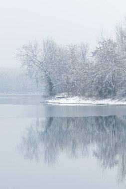 Kış gölü sahnesi suda yansıyor.