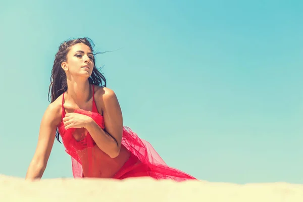 Fashion portrait of a young girl in a red dress on blue sky and — Stock Photo, Image