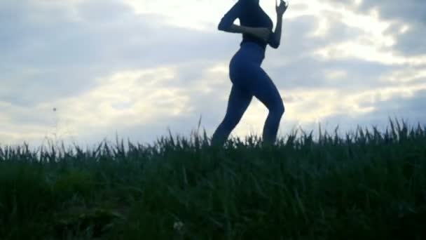 日の出シルエット背景で走っている女性を閉じる動きを遅きます 女の子ジョギング サイドビュー トラッキング ショットをクローズ アップ黄金の日の出 — ストック動画