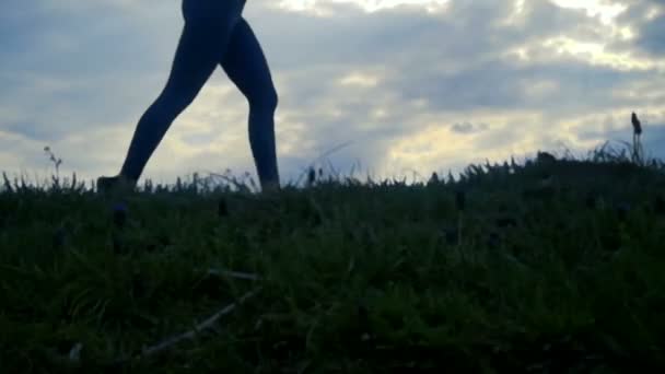 日の出シルエット背景で走っている女性を閉じる動きを遅きます 女の子ジョギング サイドビュー トラッキング ショットをクローズ アップ黄金の日の出 — ストック動画