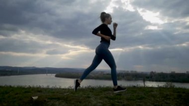 Gün batımında, siluet çalışan genç kadın çalışan ağır çekim genç kadın. Ağır çekim, güzel bulutlar, atletik kadın çalışma dışarı açık koşu