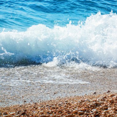 Çakıl taşları plajındaki Mavi Okyanus Dalgası Yaz Arkaplanı