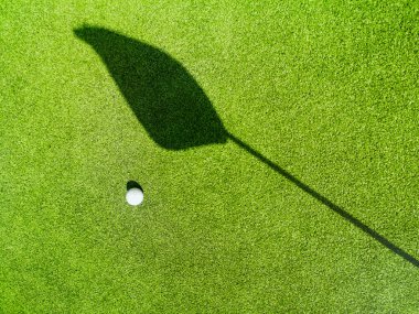 Yeşilde golf topu, yeşilde bayrağın gölgesi, golf sahası