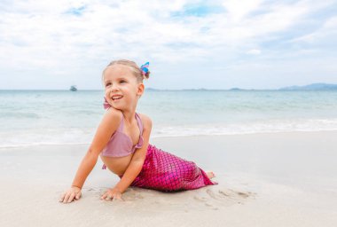 Deniz kızı deniz kıyısı üzerinde oturur gibi mayo giymiş küçük güzel kız