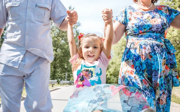 family, generation and people concept - happy smiling grandmother, grandfather and little granddaughter walking at park