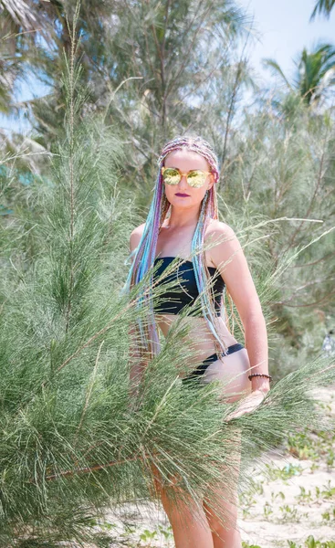 Сексуальная девушка в купальнике с косичками и солнцезащитными очками на елке — стоковое фото