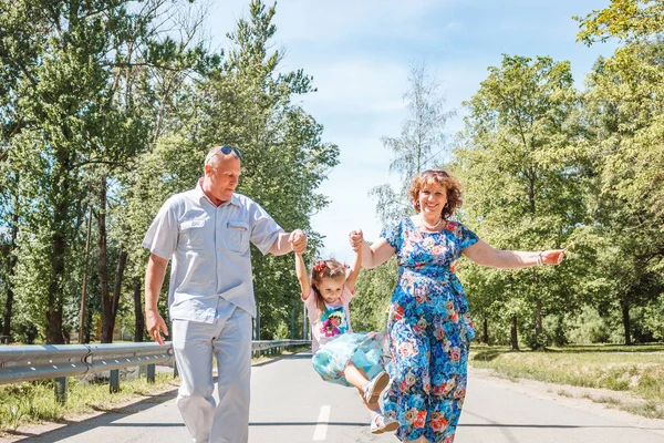 家庭、 一代人和人的概念 — — 快乐微笑的祖母、 祖父和小孙女在公园散步 图库照片