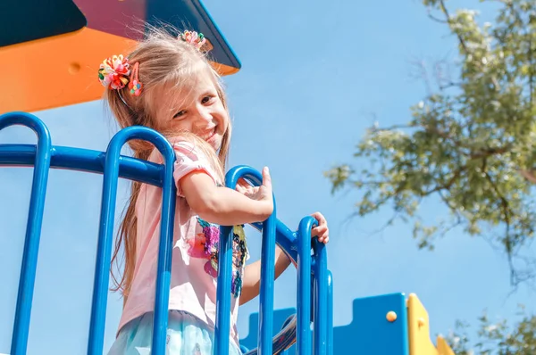 Leende liten flicka vid lekplatsen i parken Royaltyfria Stockbilder