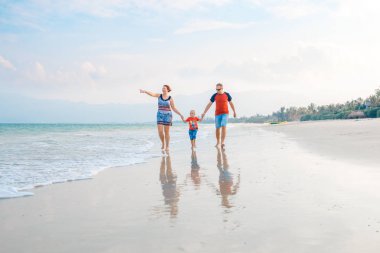 Mutlu aile tatil. Anne, baba ve küçük oğlu deniz kıyısı yürüyor. Aile seyahat
