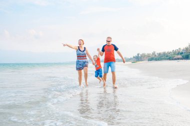 Mutlu aile tatil. Anne, baba ve küçük oğlu deniz kıyısı yürüyor. Aile seyahat