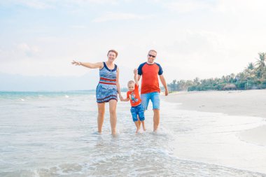 Mutlu aile tatil. Anne, baba ve küçük oğlu deniz kıyısı yürüyor. Aile seyahat