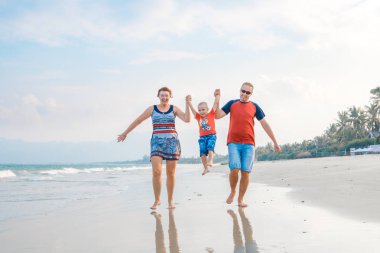 Mutlu aile tatil. Anne, baba ve küçük oğlu deniz kıyısı yürüyor. Aile seyahat