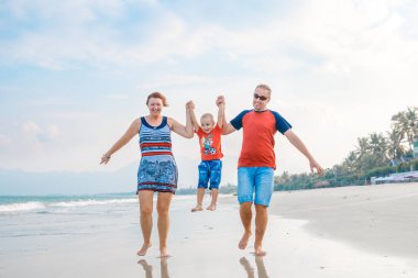 Mutlu aile tatil. Anne, baba ve küçük oğlu deniz kıyısı yürüyor. Aile seyahat