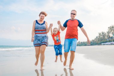 Mutlu aile tatil. Anne, baba ve küçük oğlu deniz kıyısı yürüyor. Aile seyahat