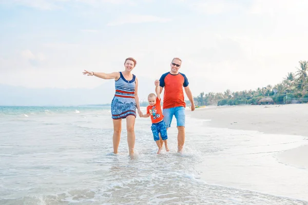 Mutlu aile tatil. Anne, baba ve küçük oğlu deniz kıyısı yürüyor. Aile seyahat