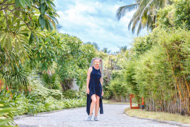 siyah elbise ve güneş gözlüğü pigtails kız ağaçlar arasında yürüyor