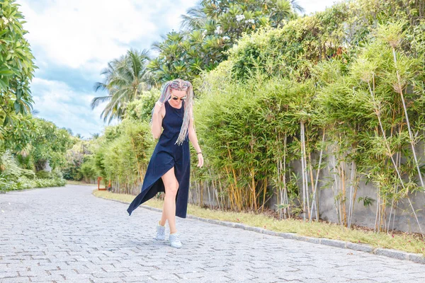 나무 사이 검은 드레스와 선글라스 땋은 소녀 산책 — 스톡 사진